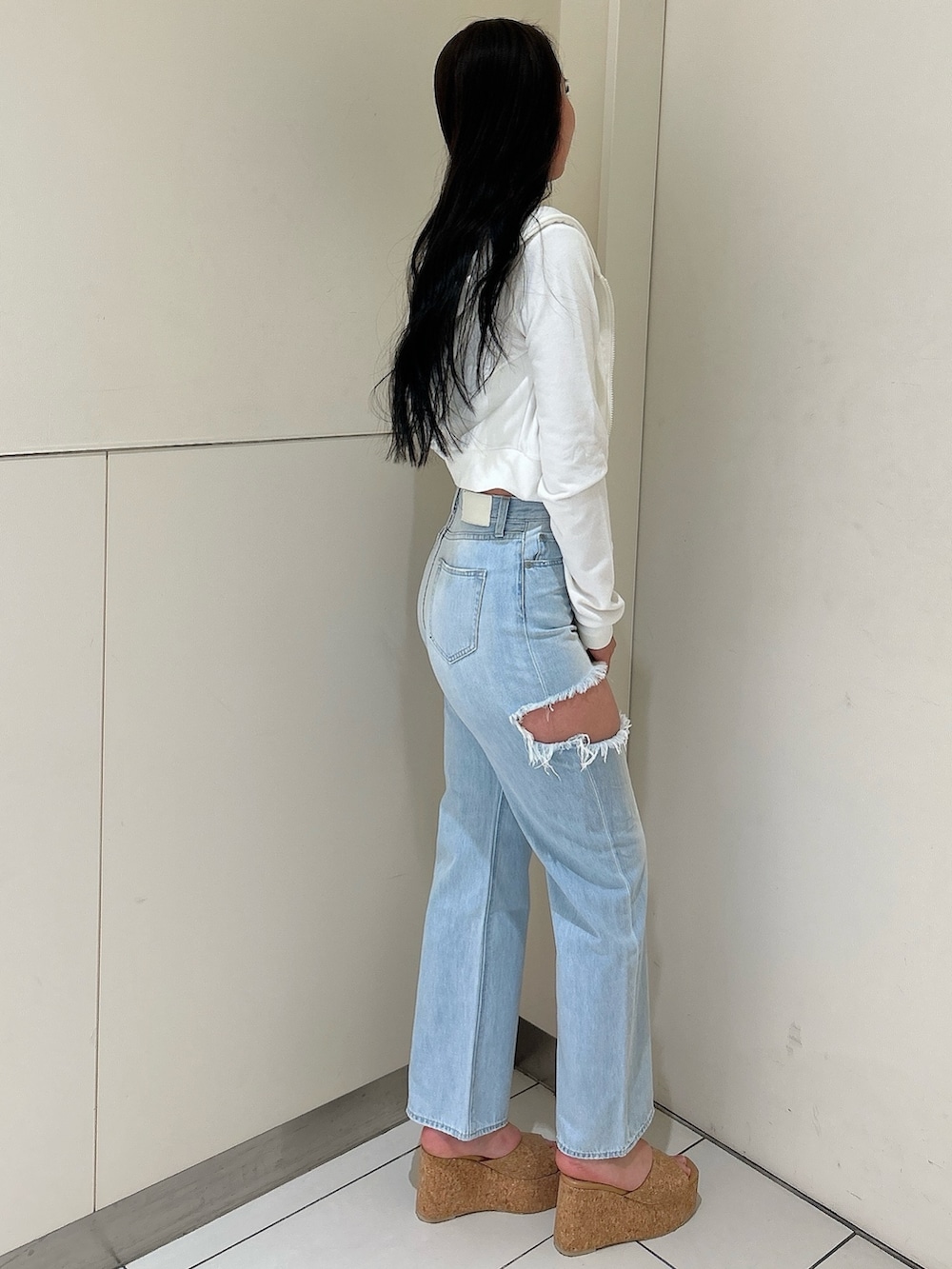 ホワイト系のパーカー、ブルー系のデニムパンツ、ホワイト系のチューブトップを着用したレディースの春コーディネートの2枚目の写真