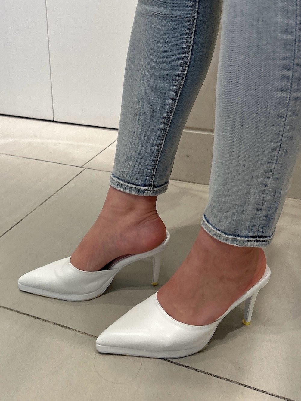 イエロー系のスウェット、ホワイト系のショルダーバッグ、ホワイト系のパンプスを着用したレディースの冬コーディネートの8枚目の写真
