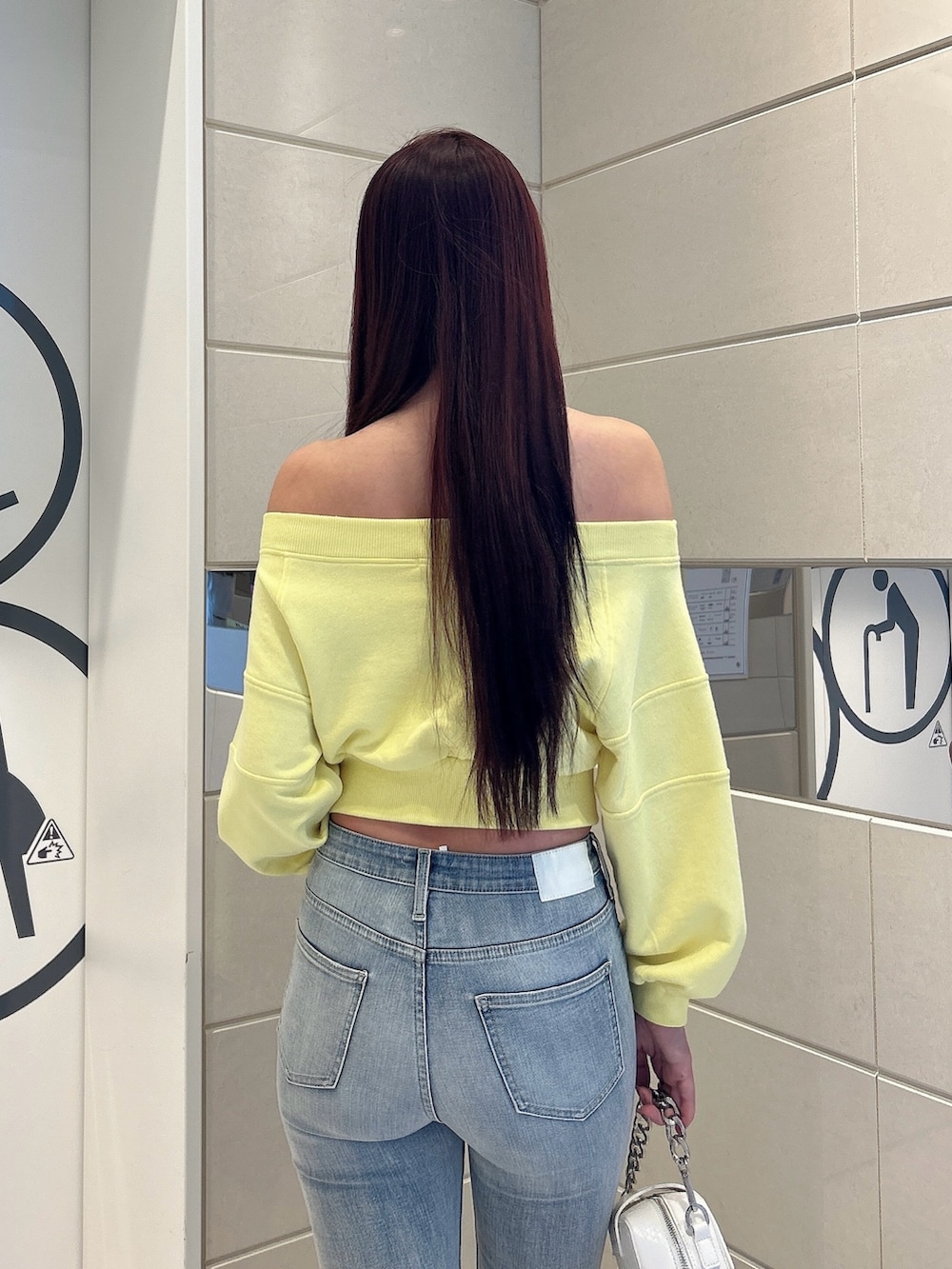 イエロー系のスウェット、ホワイト系のショルダーバッグ、ホワイト系のパンプスを着用したレディースの冬コーディネートの6枚目の写真