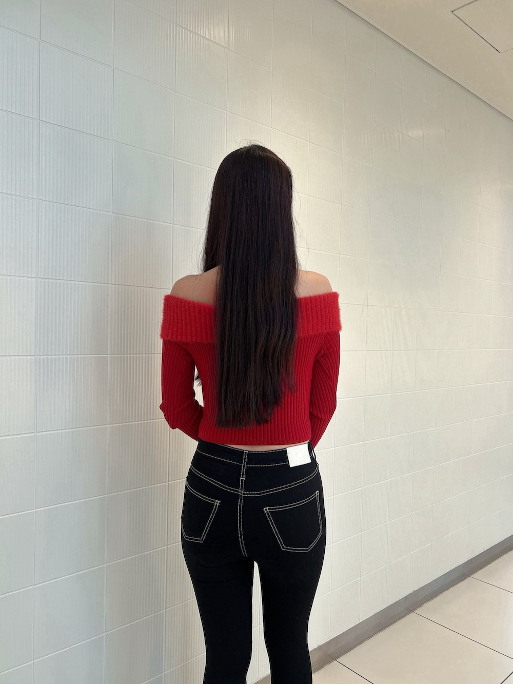 レッド系のニット/セーター、ブルー系のデニムパンツ、ブラック系のブーツを着用したレディースの冬コーディネートの6枚目の写真