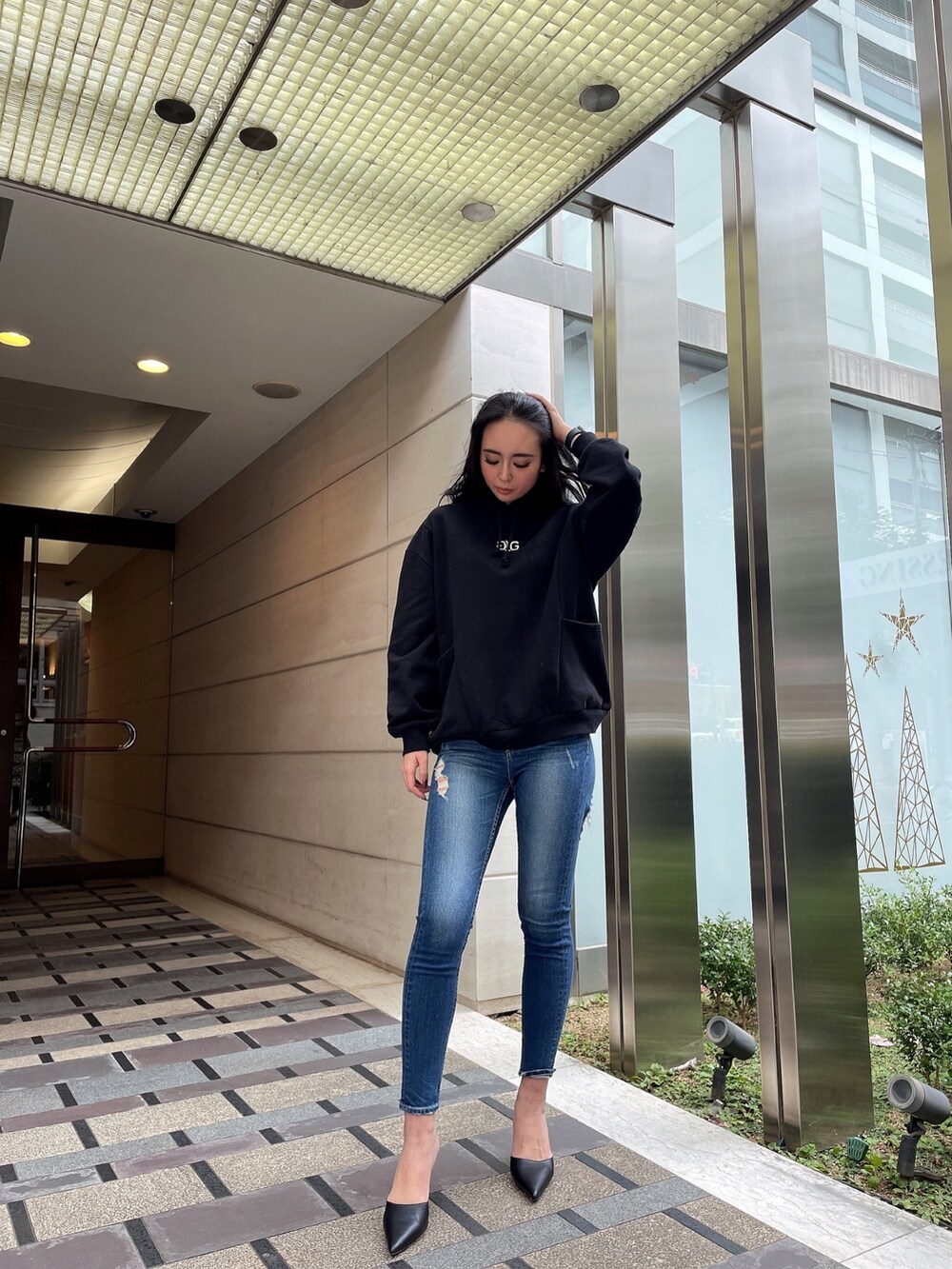 ブルー系のデニムパンツ、ブラック系のスウェット、ブラック系のパンプスを着用したレディースの冬コーディネートの3枚目の写真