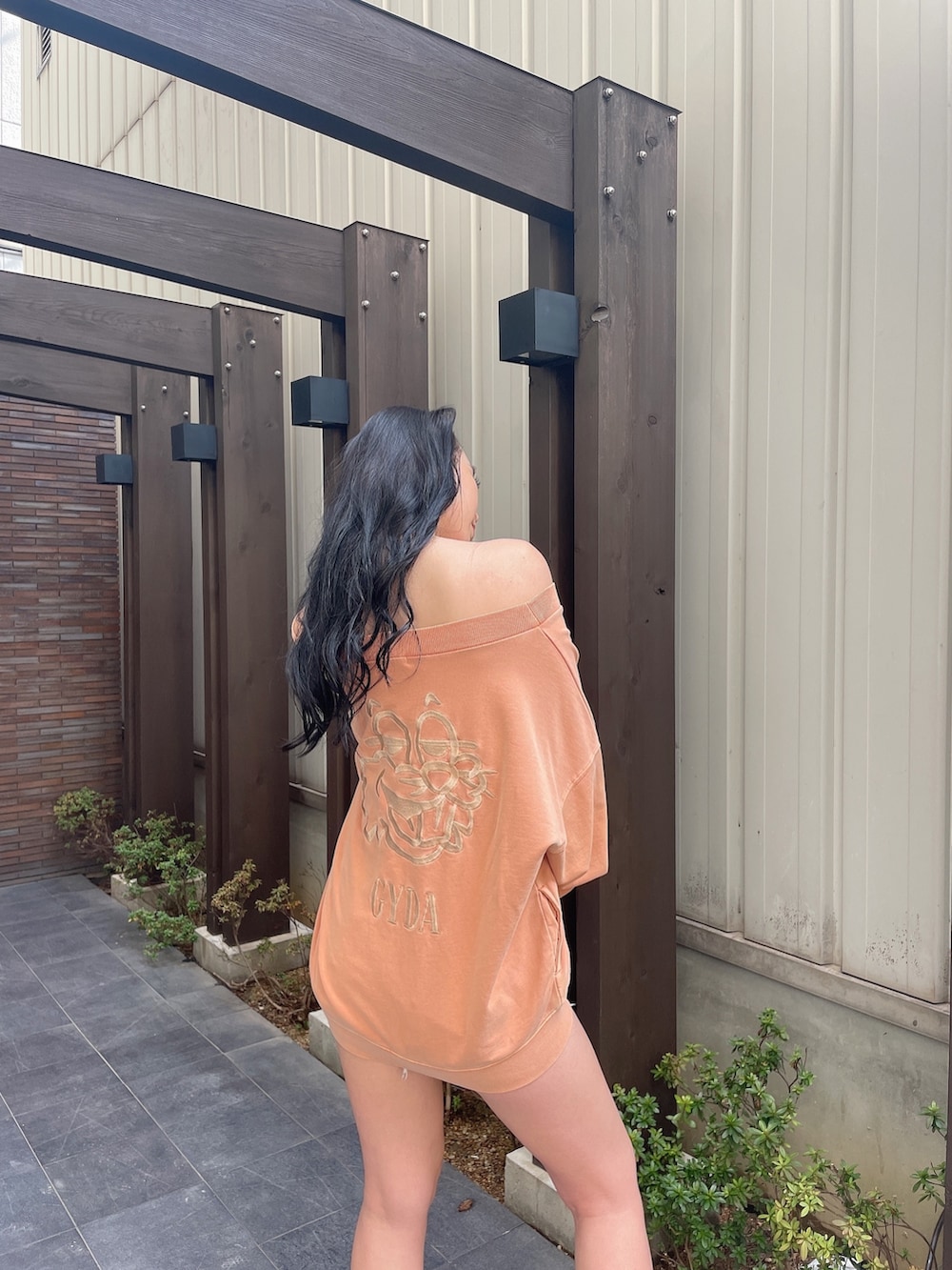 オレンジ系のスウェット、ブルー系のデニムパンツ、ブラック系のブーツを着用したレディースの冬コーディネートの5枚目の写真