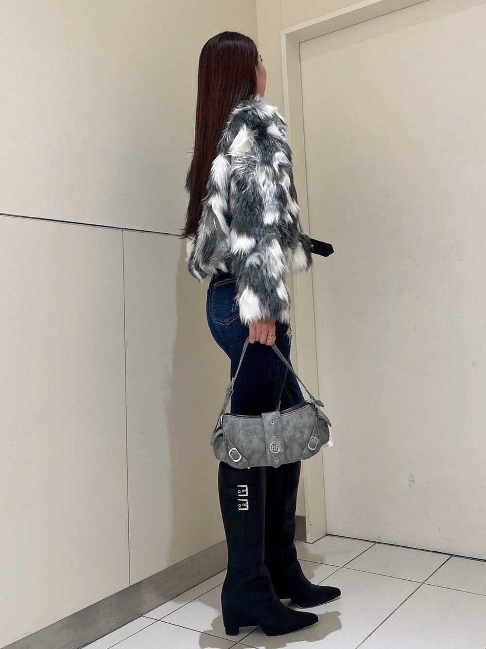 ブルー系のデニムパンツ、ブラック系のブーツ、グリーン系のショルダーバッグを着用したレディースの秋コーディネートの2枚目の写真