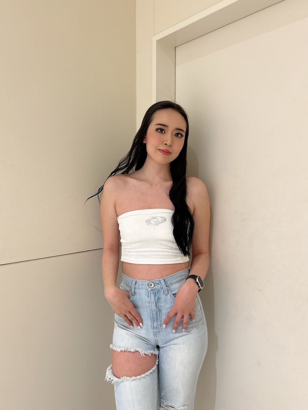 ホワイト系のパーカー、ブルー系のデニムパンツ、ホワイト系のチューブトップを着用したレディースの春コーディネートの4枚目の写真