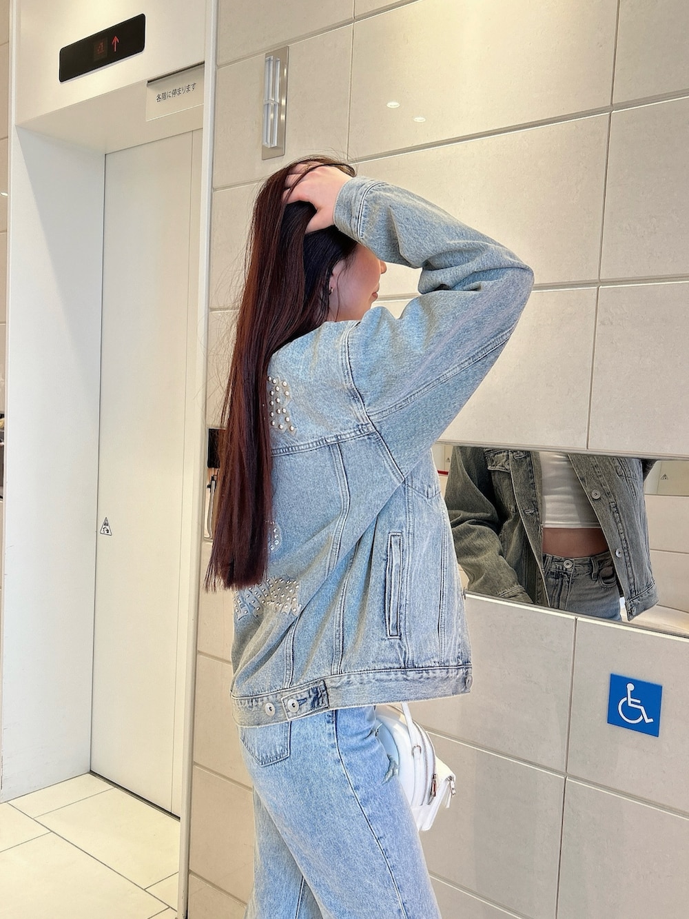 ホワイト系のパンプス、ブルー系のデニムジャケット、ホワイト系のキャミソールを着用したレディースの春コーディネートの5枚目の写真