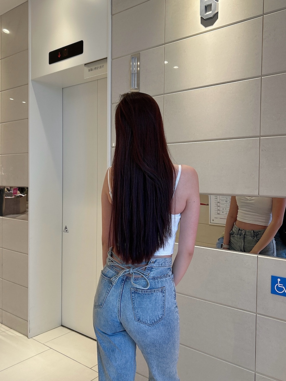 ホワイト系のキャミソール、ブルー系のデニムパンツ、ホワイト系のパンプスを着用したレディースの春コーディネートの6枚目の写真