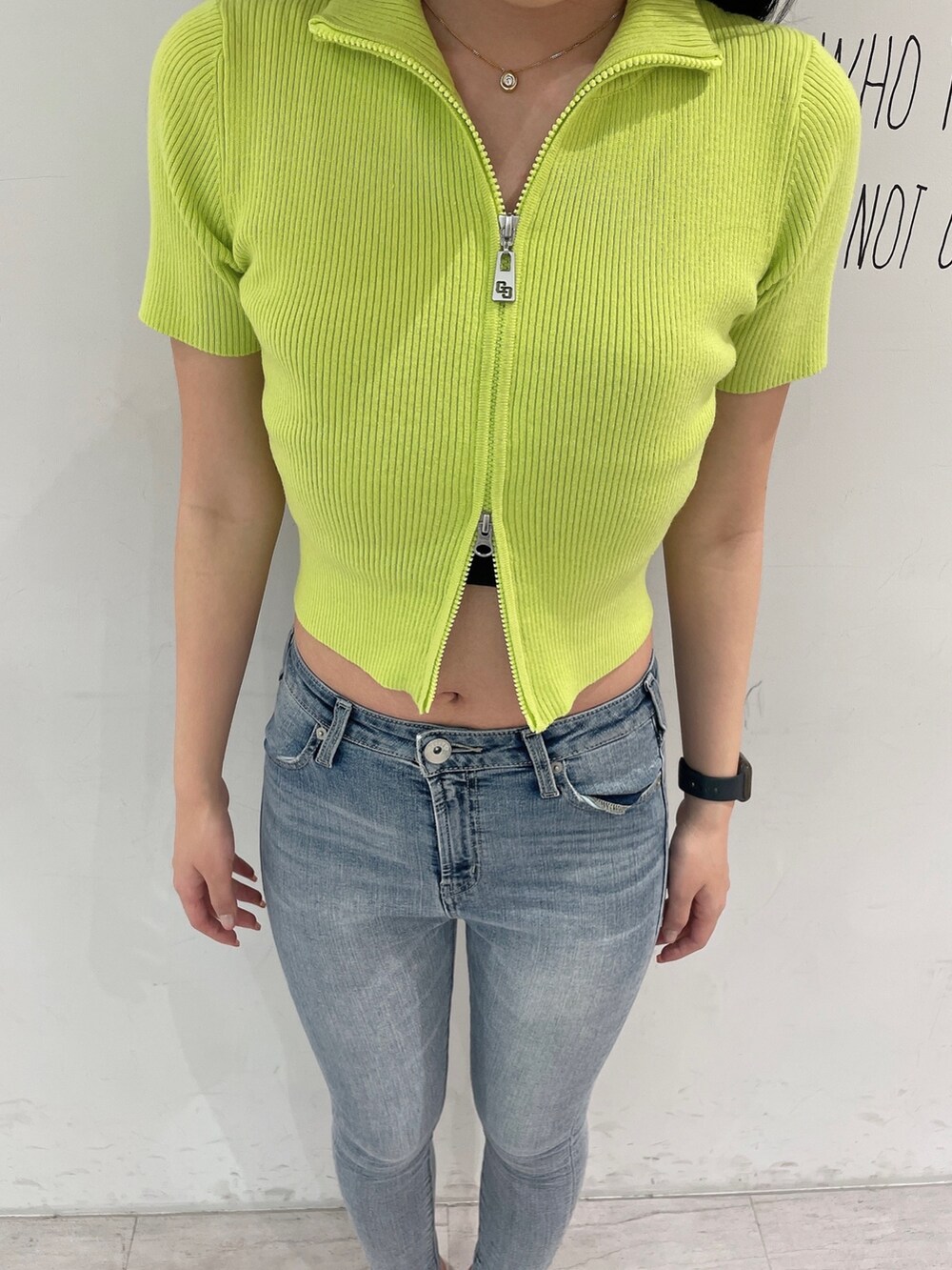 グリーン系のニット/セーター、ブルー系のデニムパンツ、ホワイト系のパンプスを着用したレディースの春コーディネートの5枚目の写真