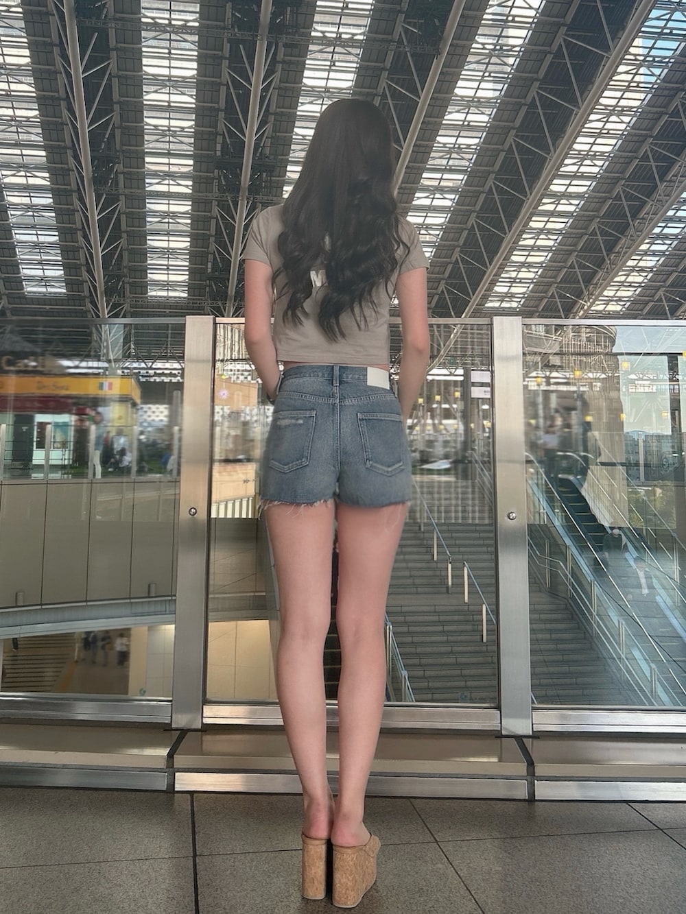 ベージュ系のTシャツ/カットソー、ブルー系のデニムパンツ、ベージュ系のサンダルを着用したレディースの夏コーディネートの3枚目の写真