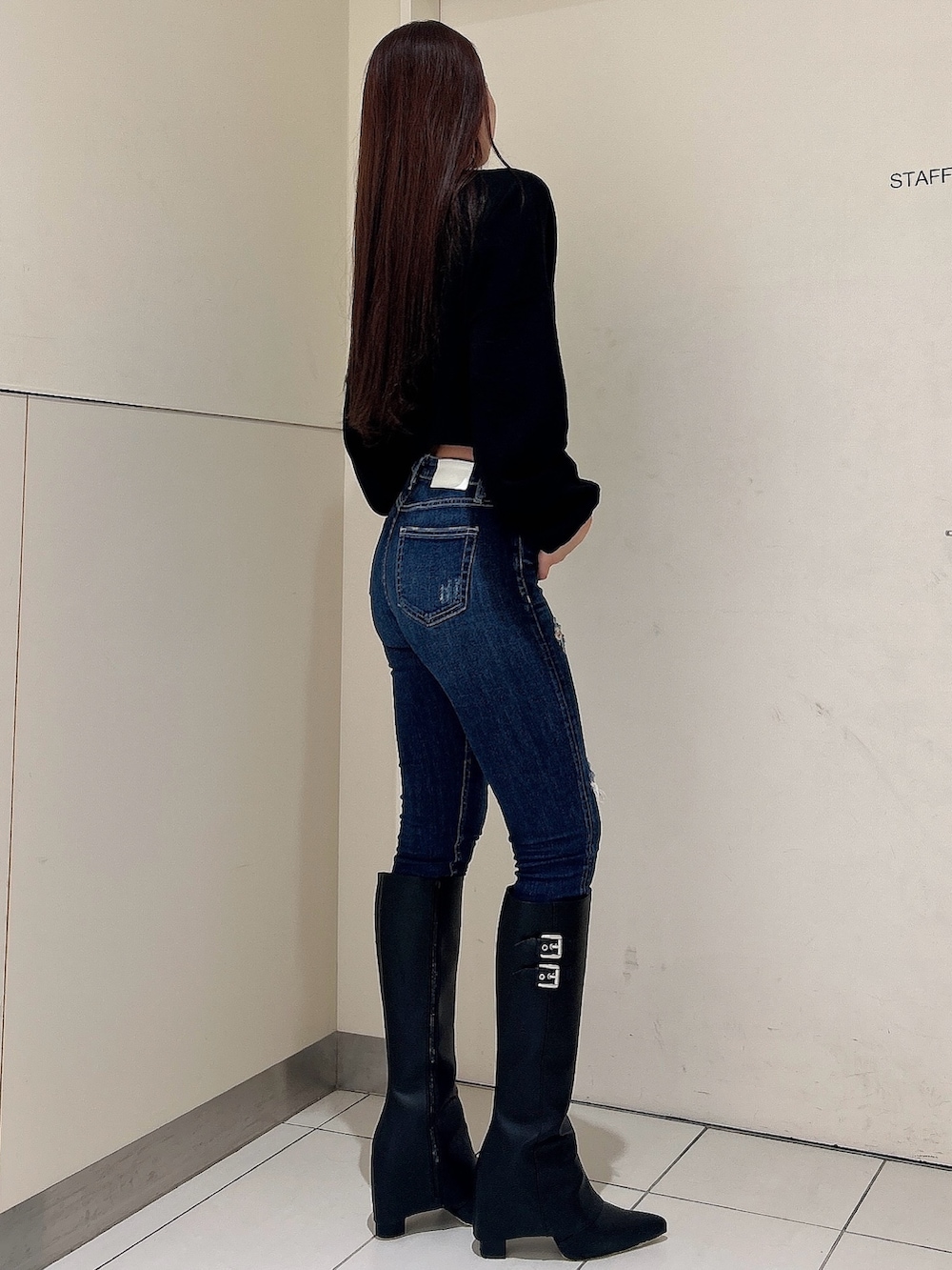 ブラック系のニット/セーター、ブラック系のブーツ、ブルー系のデニムパンツを着用したレディースの秋コーディネートの2枚目の写真