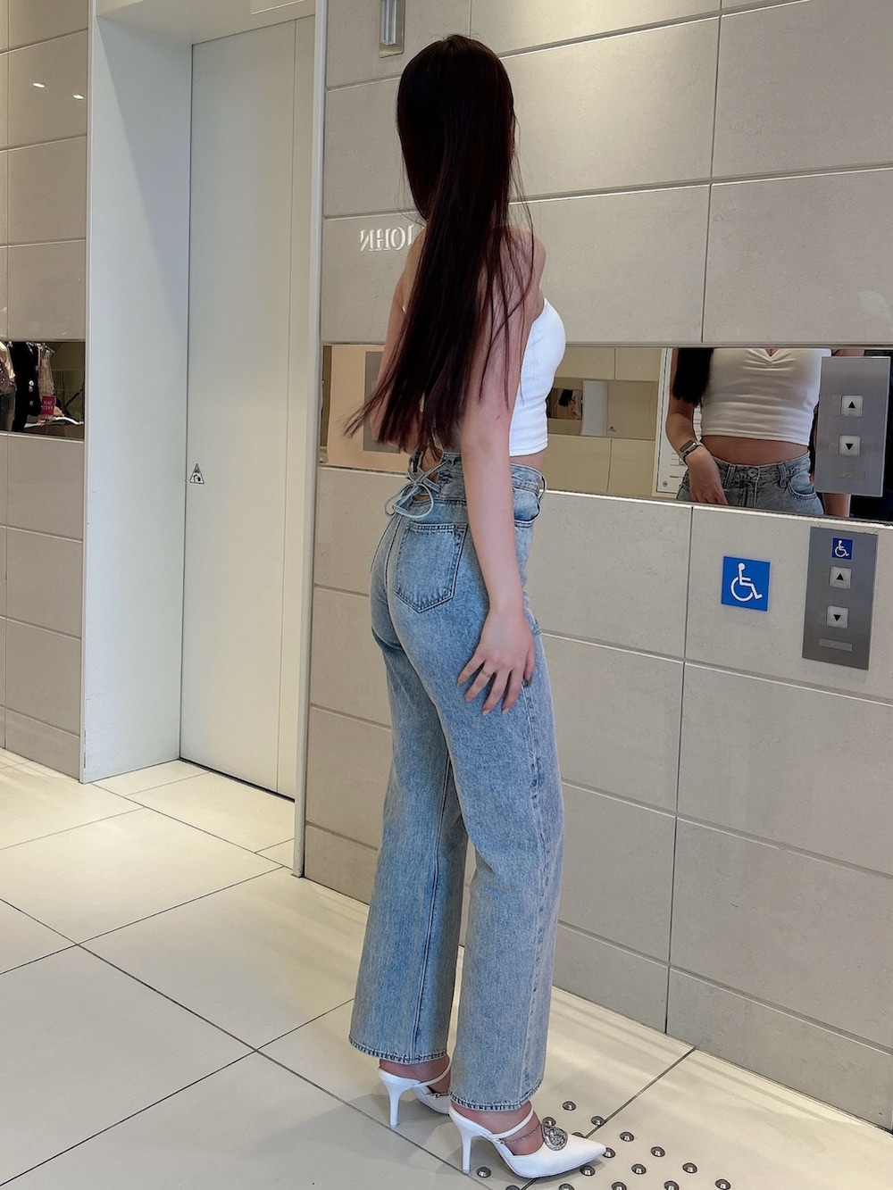 ホワイト系のキャミソール、ブルー系のデニムパンツ、ホワイト系のパンプスを着用したレディースの春コーディネートの2枚目の写真