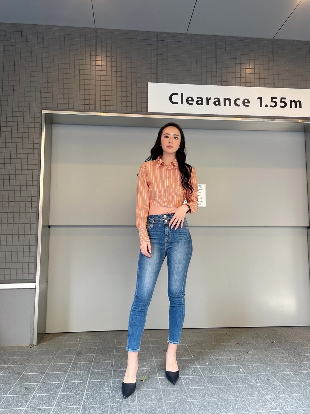 ブルー系のデニムパンツ、オレンジ系のシャツ/ブラウス、ブラック系のパンプスを着用したレディースの冬コーディネートの3枚目の写真