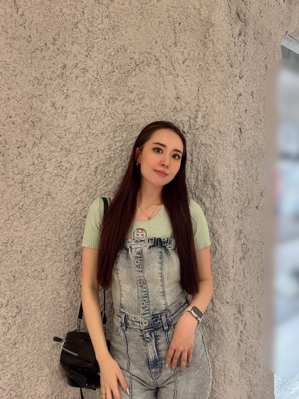 グリーン系のニット/セーター、ブルー系のつなぎ/オールインワン、ブラック系のバックパック/リュックを着用したレディースの春コーディネートの4枚目の写真