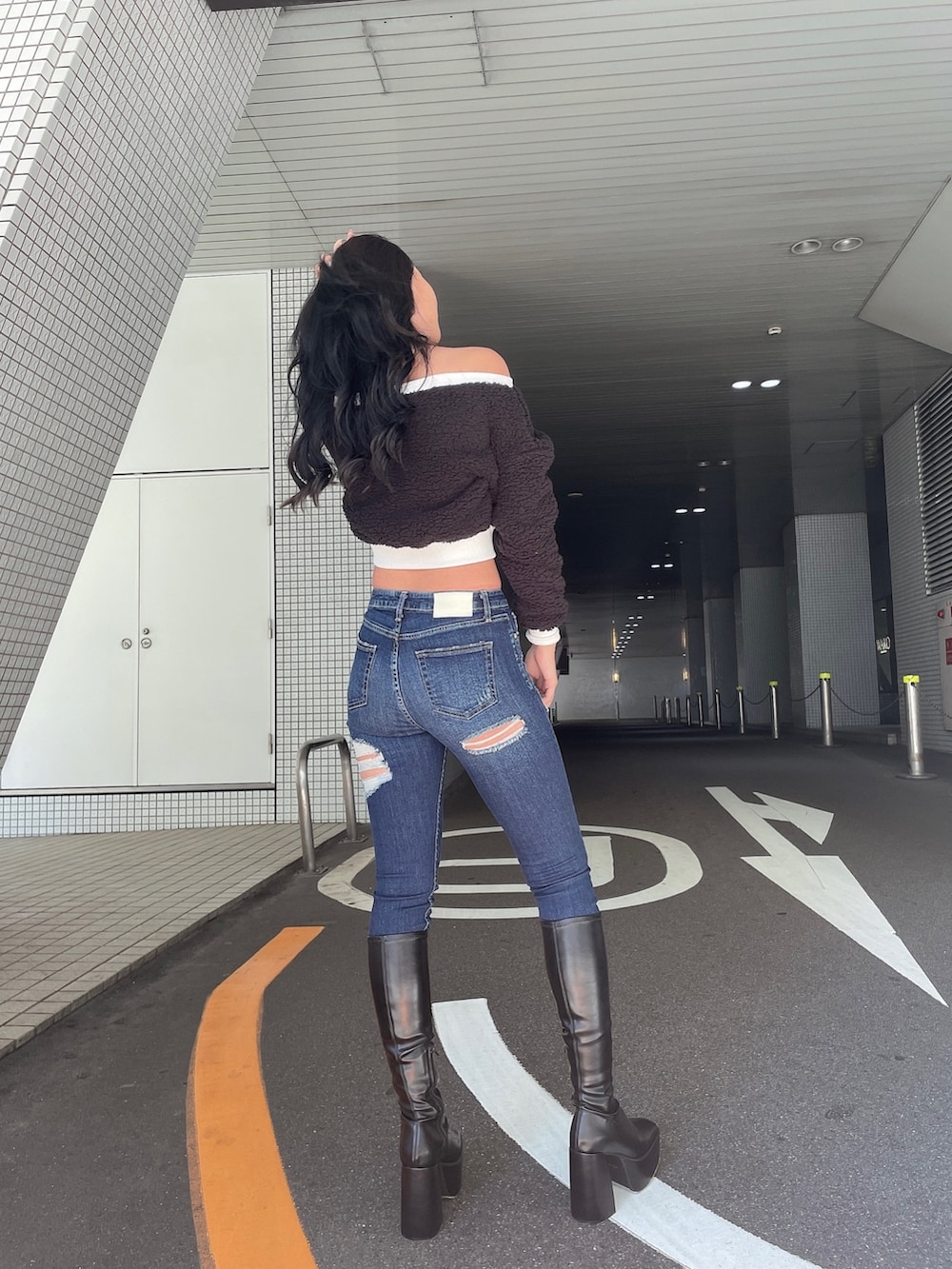 ブラック系のTシャツ/カットソー、ブルー系のデニムパンツ、ブラック系のブーツを着用したレディースの秋コーディネートの5枚目の写真