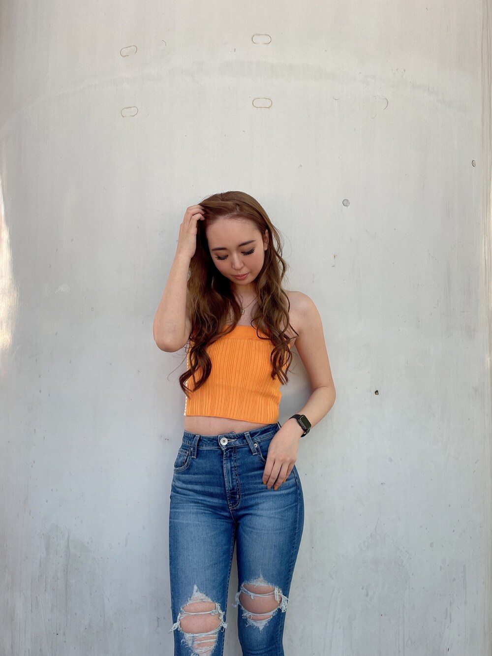 オレンジ系のニット/セーター、ブルー系のデニムパンツ、ベージュ系のサンダルを着用したレディースの春コーディネートの3枚目の写真