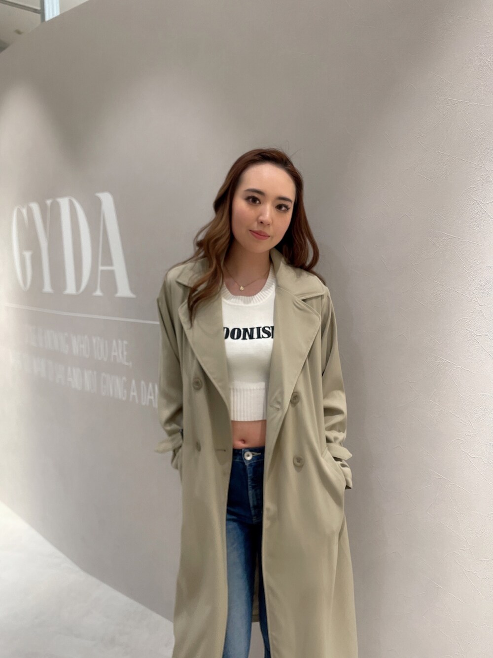 ブルー系のデニムパンツ、ホワイト系のTシャツ/カットソー、ベージュ系のトレンチコートを着用したレディースの春コーディネートの3枚目の写真