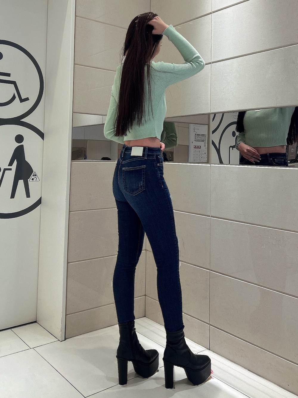 グリーン系のニット/セーター、ブルー系のデニムパンツ、ブラック系のブーツを着用したレディースの冬コーディネートの2枚目の写真