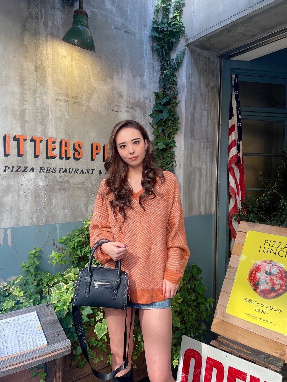 ブルー系のデニムスカート、ブラック系のボストンバッグ、オレンジ系のニット/セーターを着用したレディースの秋コーディネートの4枚目の写真