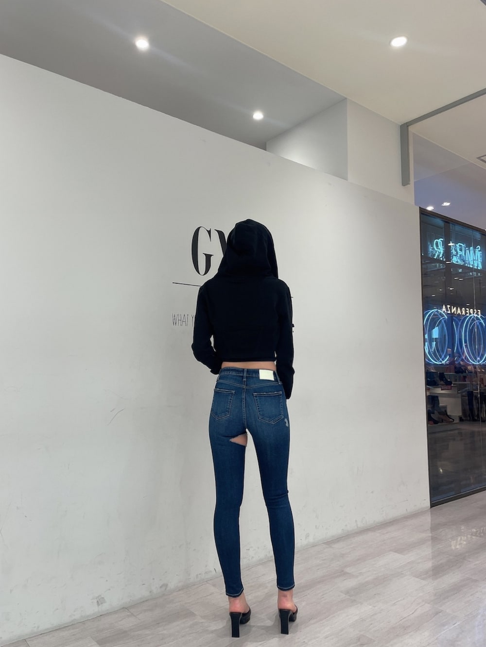 ブラック系のパーカー、ホワイト系のキャミソール、ブルー系のデニムパンツを着用したレディースの冬コーディネートの2枚目の写真