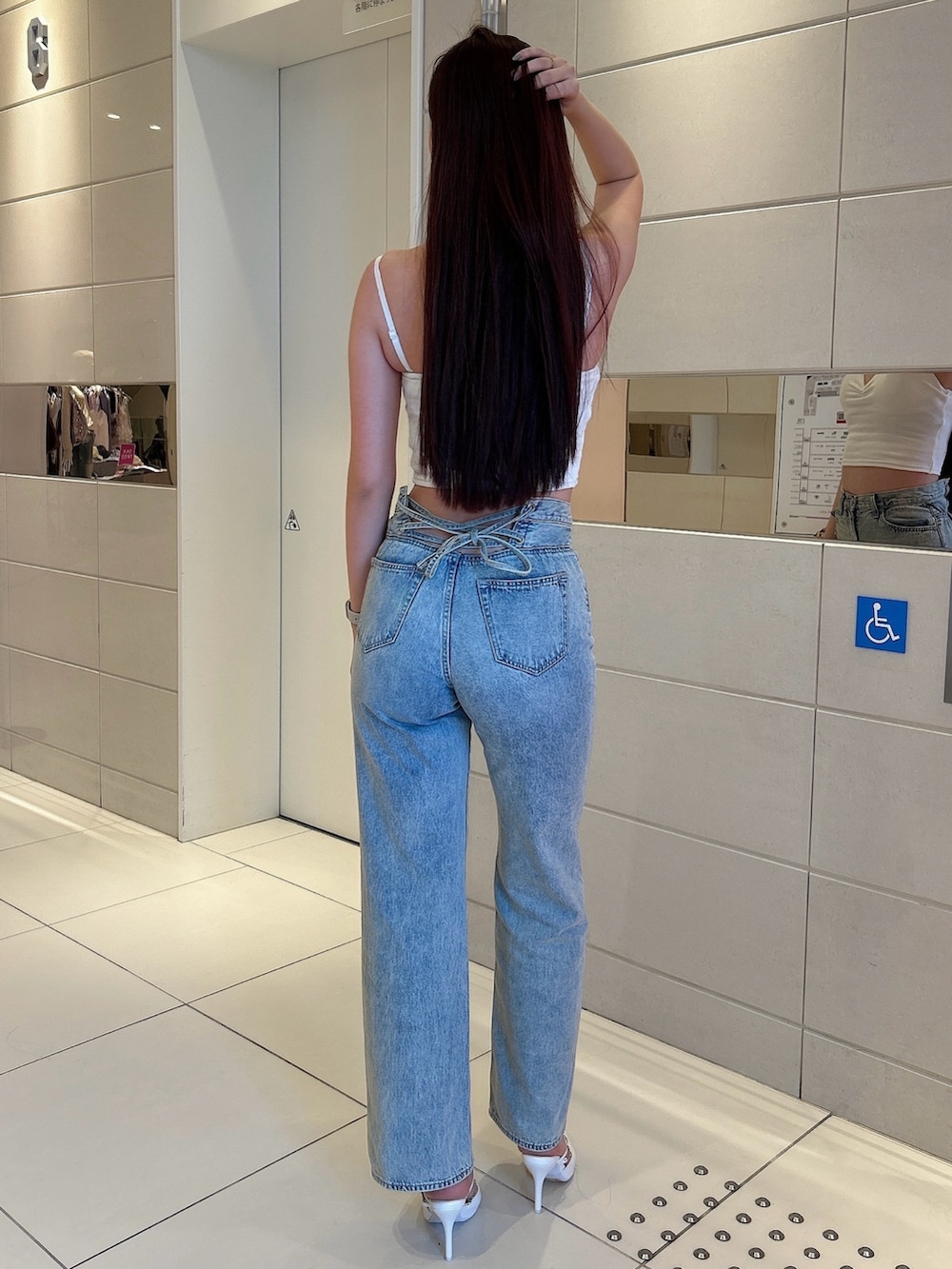 ホワイト系のキャミソール、ブルー系のデニムパンツ、ホワイト系のパンプスを着用したレディースの春コーディネートの3枚目の写真