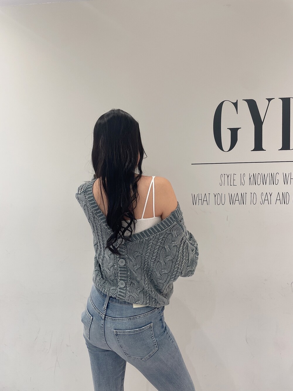 グリーン系のニット/セーター、ブルー系のデニムパンツ、ホワイト系のパンプスを着用したレディースの春コーディネートの5枚目の写真