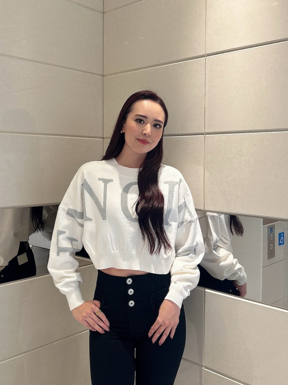 ホワイト系のニット/セーター、ブラック系のデニムパンツ、ブラック系のブーツを着用したレディースの冬コーディネートの4枚目の写真