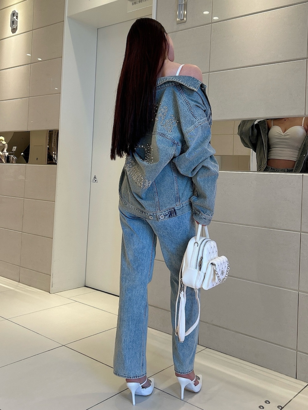 ホワイト系のパンプス、ブルー系のデニムジャケット、ホワイト系のキャミソールを着用したレディースの春コーディネートの3枚目の写真