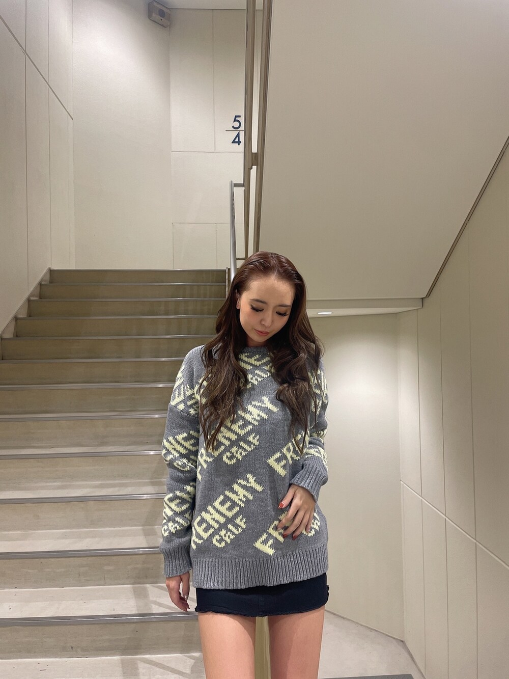 グレー系のニット/セーター、ブラック系のスカート、ブラック系のブーツを着用したレディースの秋コーディネートの4枚目の写真