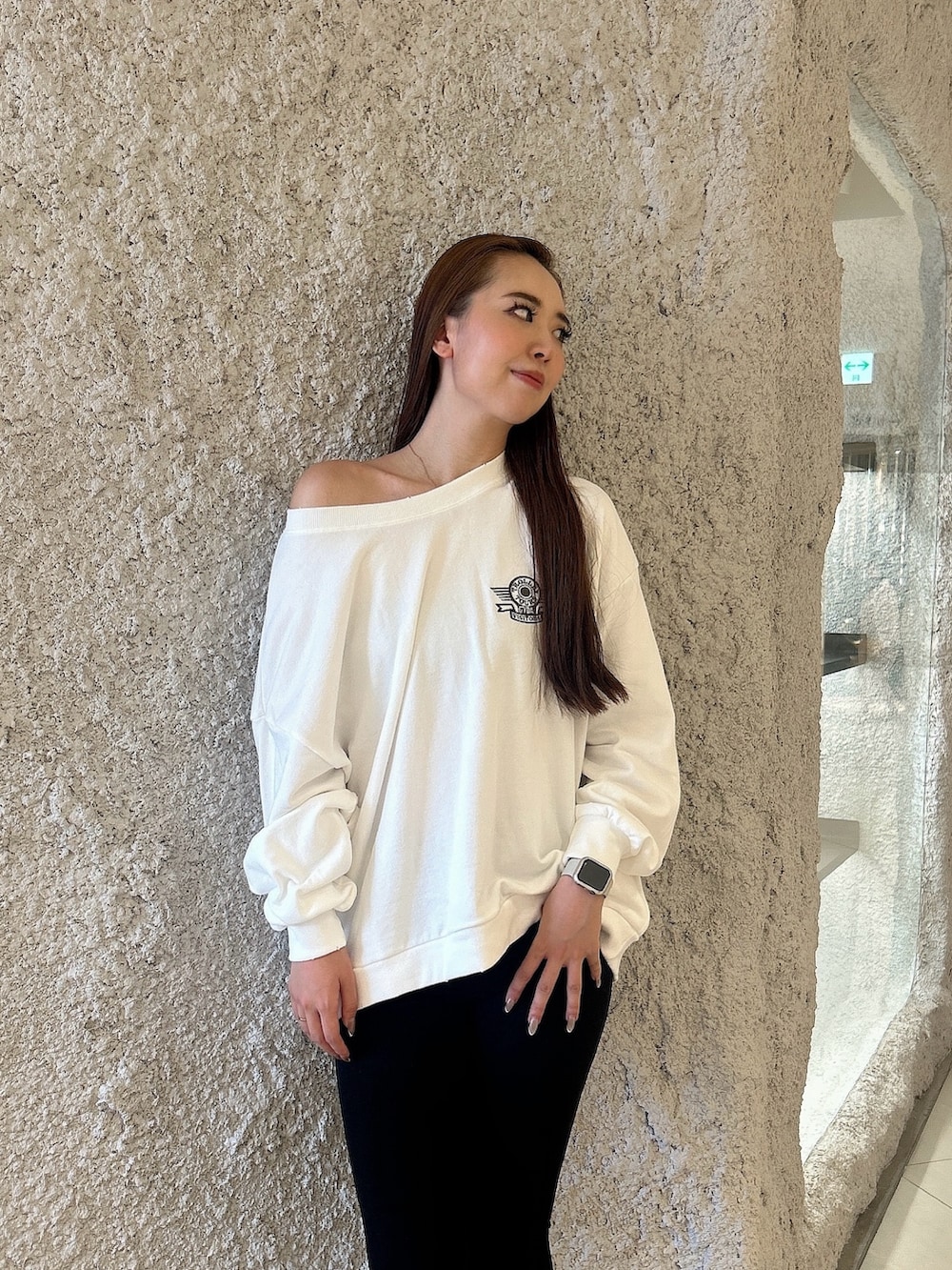 ホワイト系のスウェット、ブラック系のデニムパンツ、ブラック系のブーツを着用したレディースの秋コーディネートの4枚目の写真