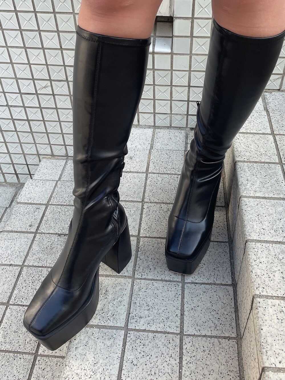 ブラック系のブルゾン、ホワイト系のワンピース、ブラック系のブーツを着用したレディースの冬コーディネートの7枚目の写真