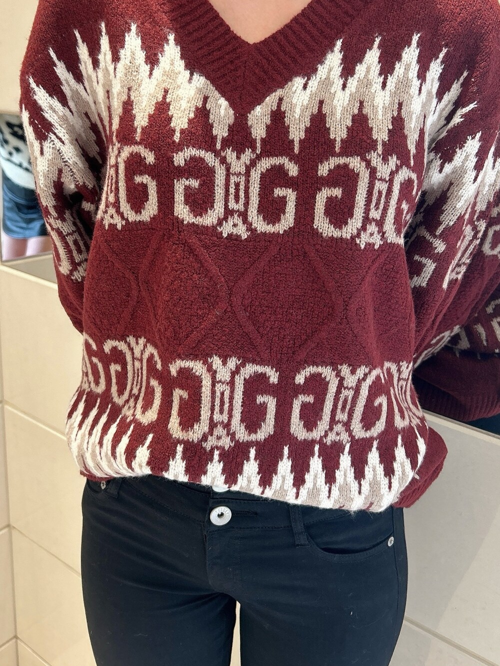 レッド系のニット/セーター、ブラック系のデニムパンツ、ブラック系のブーツを着用したレディースの冬コーディネートの7枚目の写真