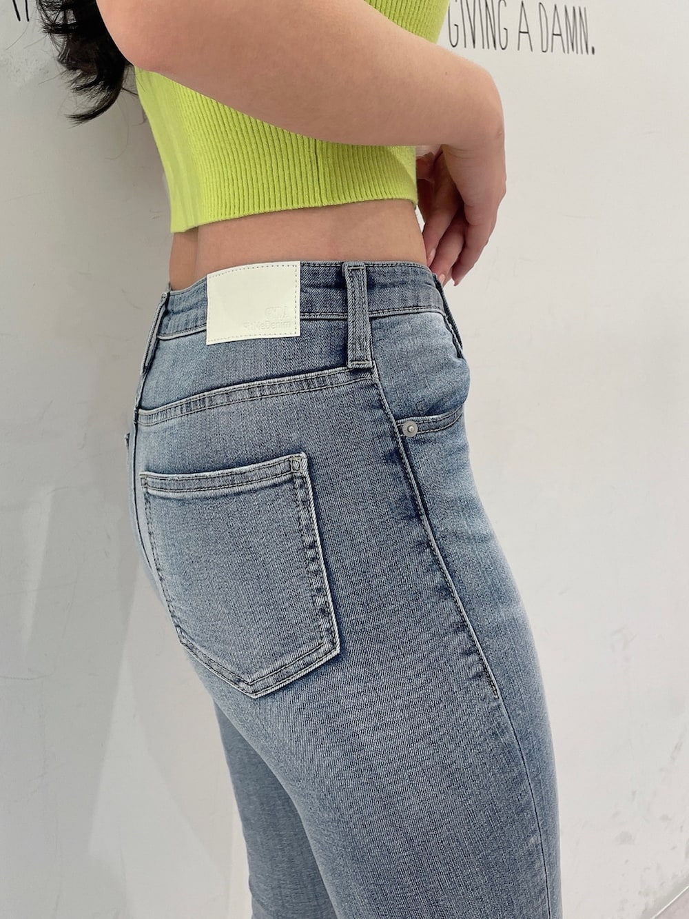 グリーン系のニット/セーター、ブルー系のデニムパンツ、ホワイト系のパンプスを着用したレディースの春コーディネートの6枚目の写真