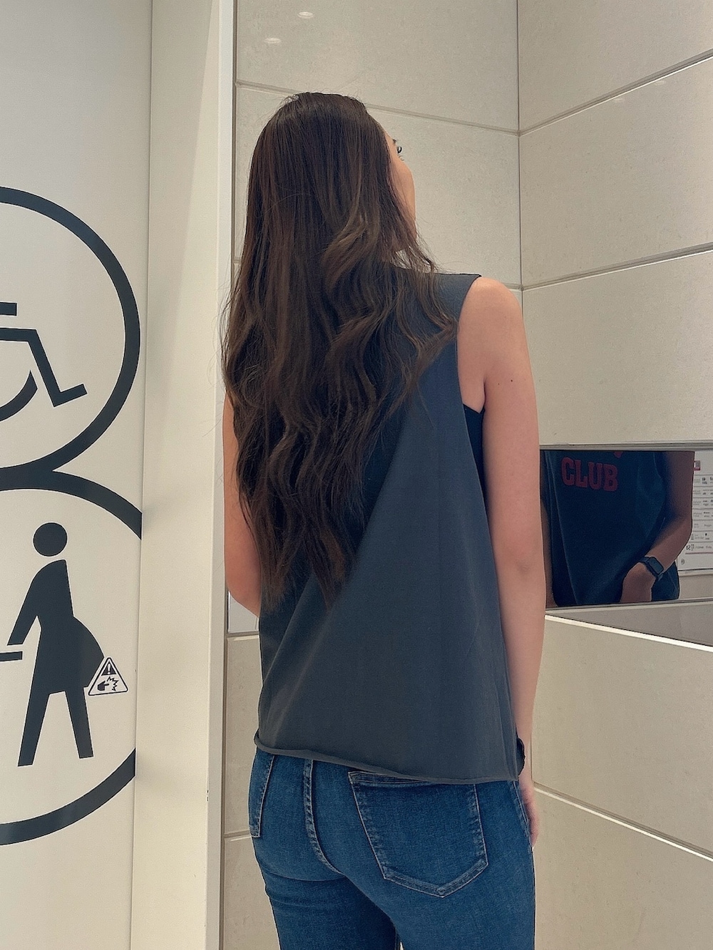 グレー系のタンクトップ、ブルー系のデニムパンツ、ベージュ系のサンダルを着用したレディースの夏コーディネートの6枚目の写真