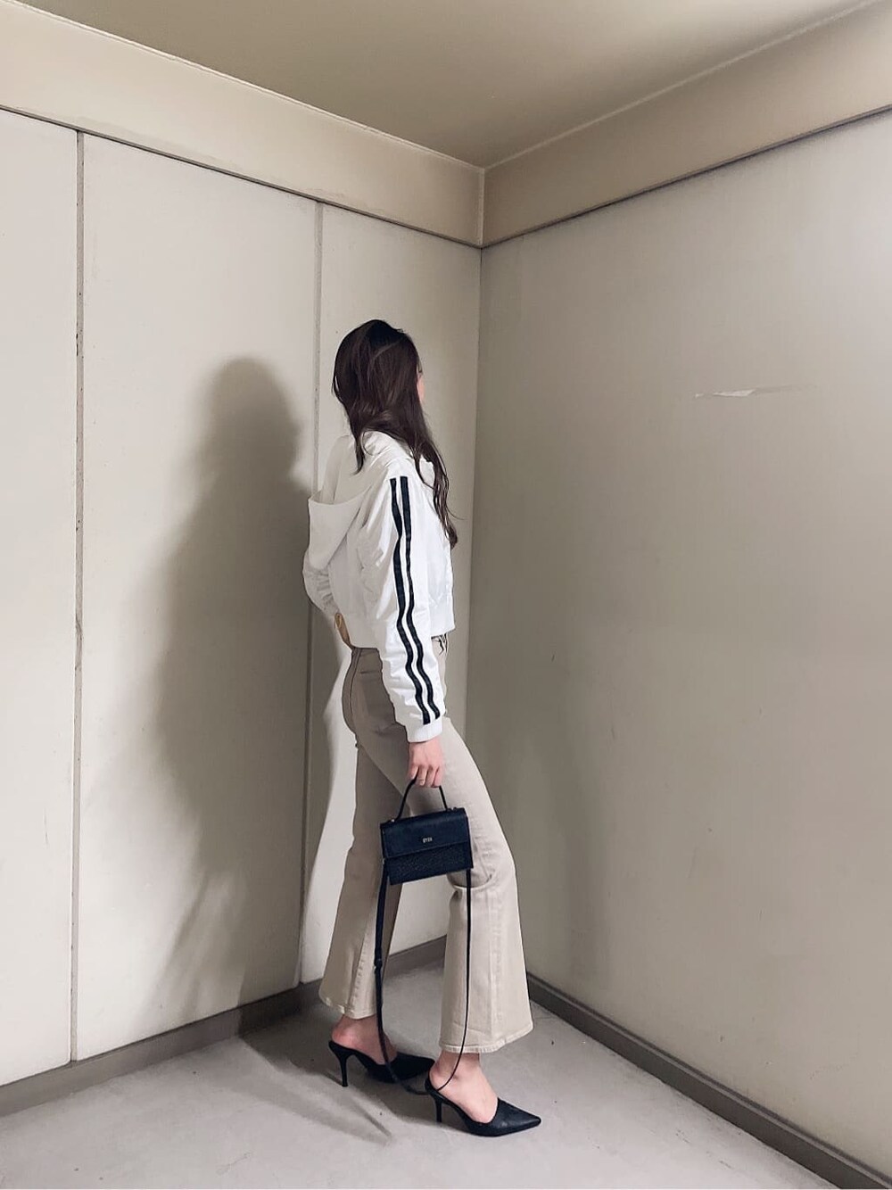 ブラック系のパンプス、ブラック系のハンドバッグ、ホワイト系のブルゾンを着用したレディースの春コーディネートの2枚目の写真