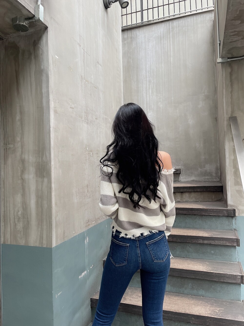 ブルー系のデニムパンツ、ブラック系のパンプス、グレー系のニット/セーターを着用したレディースの冬コーディネートの3枚目の写真