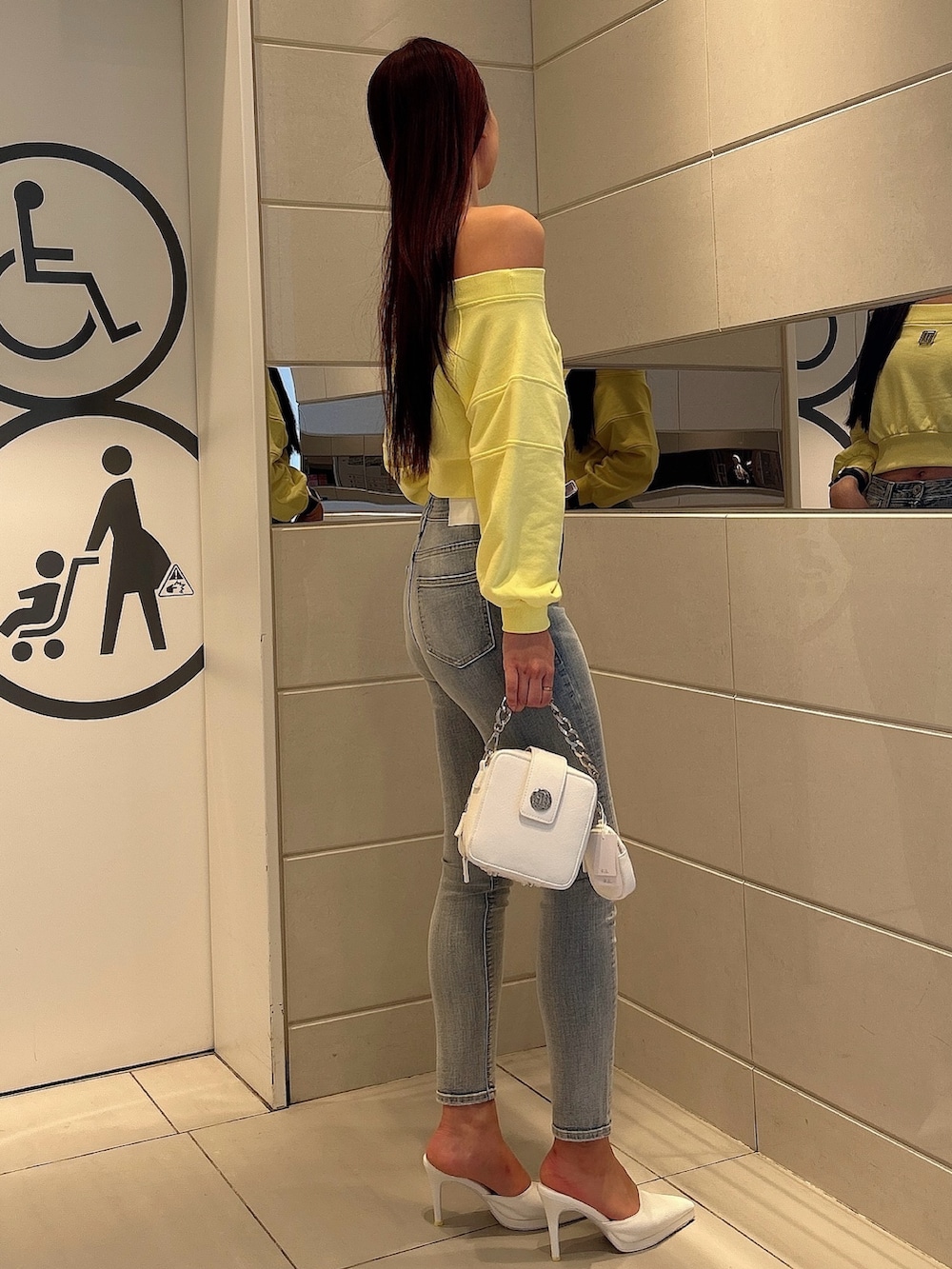イエロー系のスウェット、ホワイト系のショルダーバッグ、ホワイト系のパンプスを着用したレディースの冬コーディネートの2枚目の写真