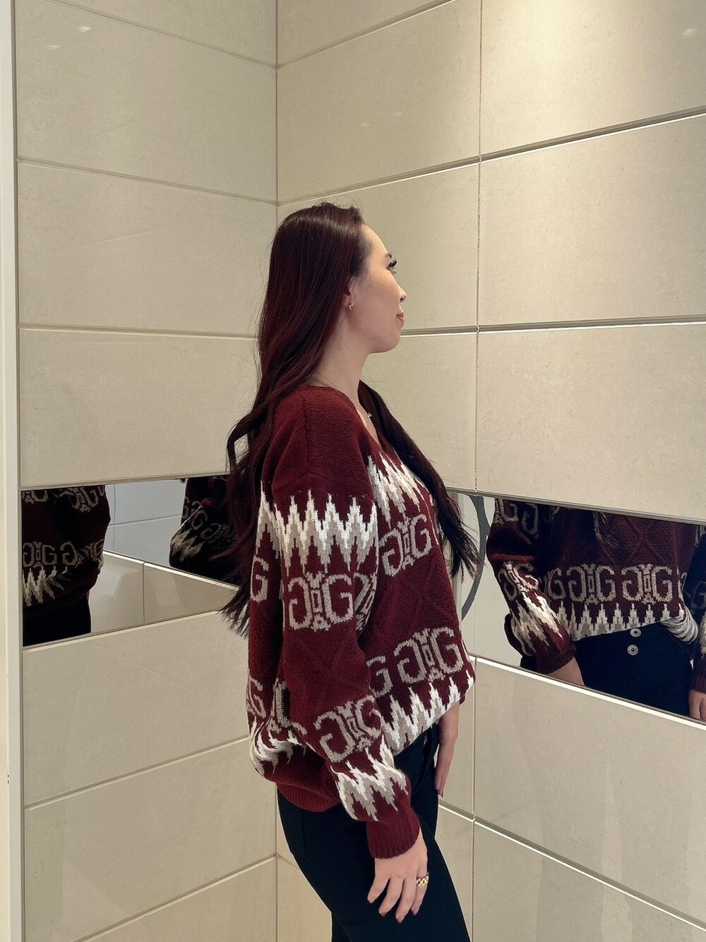 レッド系のニット/セーター、ブラック系のデニムパンツ、ブラック系のブーツを着用したレディースの冬コーディネートの5枚目の写真