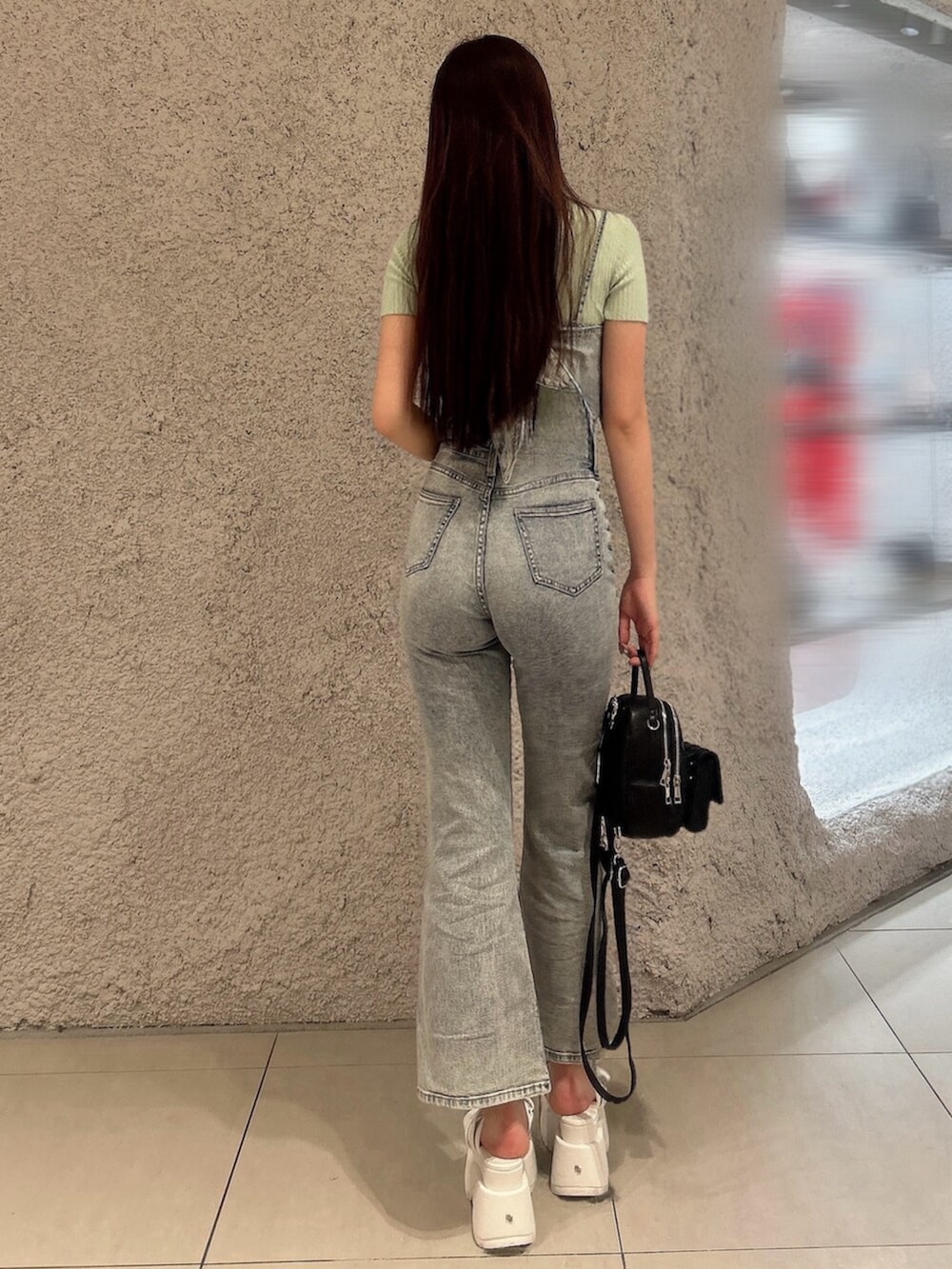 グリーン系のニット/セーター、ブルー系のつなぎ/オールインワン、ブラック系のバックパック/リュックを着用したレディースの春コーディネートの3枚目の写真