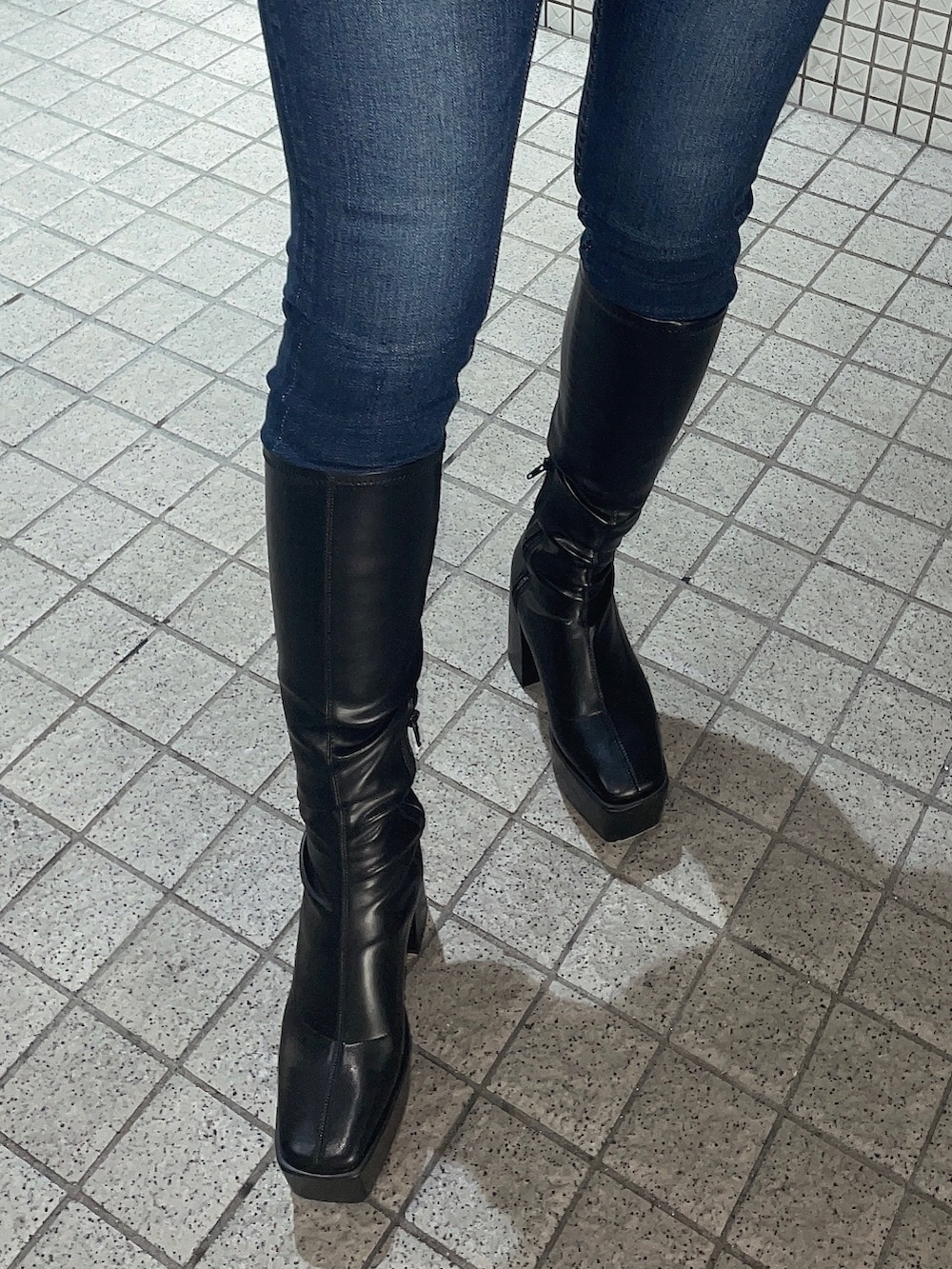 ブラック系のTシャツ/カットソー、ブルー系のデニムパンツ、ブラック系のブーツを着用したレディースの秋コーディネートの7枚目の写真