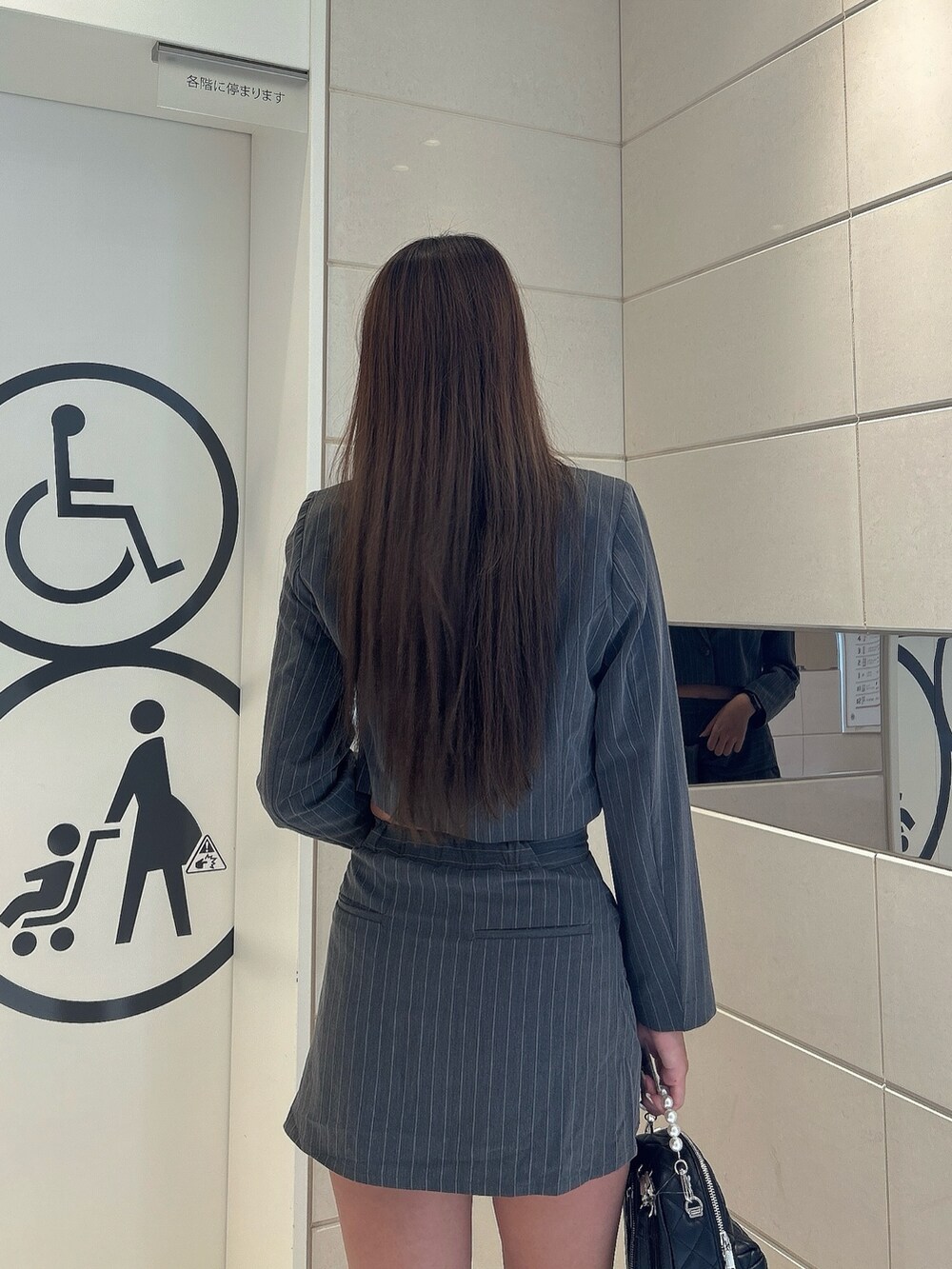 グレー系のテーラードジャケット、グレー系のスカート、ブラック系のバックパック/リュックを着用したレディースの秋コーディネートの5枚目の写真