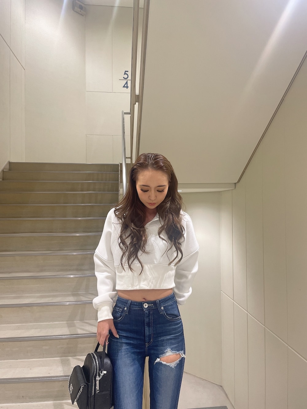 ブラック系のブーツ、ホワイト系のパーカー、ブルー系のデニムパンツを着用したレディースの秋コーディネートの3枚目の写真