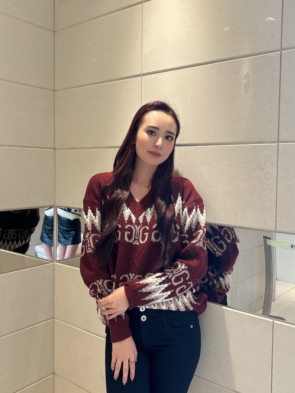 レッド系のニット/セーター、ブラック系のデニムパンツ、ブラック系のブーツを着用したレディースの冬コーディネートの4枚目の写真