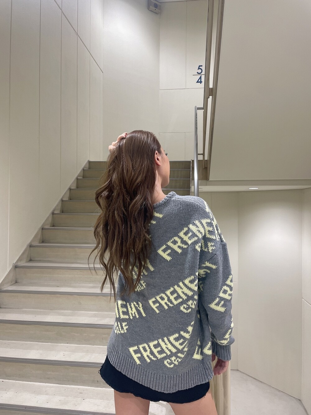 グレー系のニット/セーター、ブラック系のスカート、ブラック系のブーツを着用したレディースの秋コーディネートの5枚目の写真