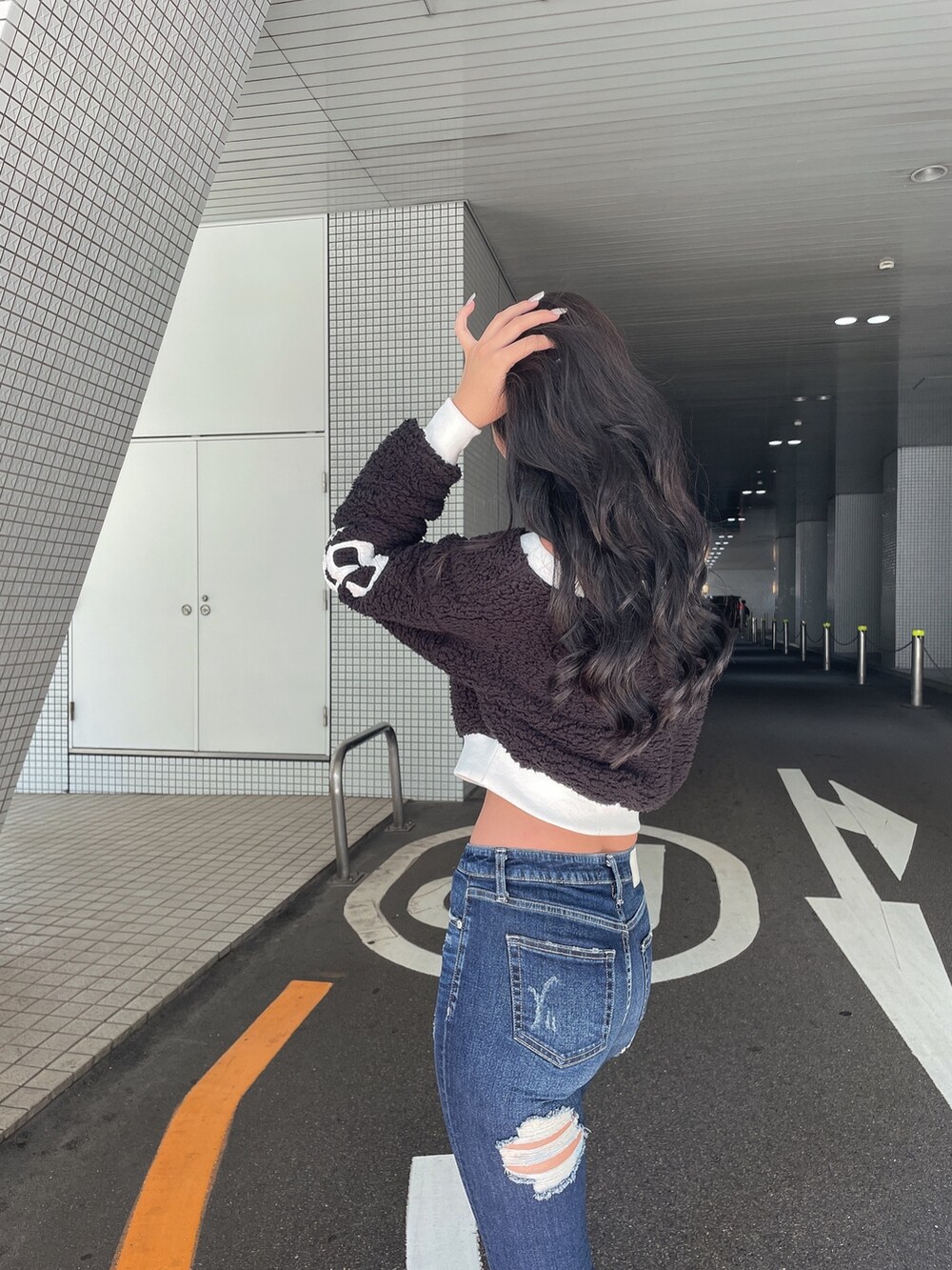 ブラック系のTシャツ/カットソー、ブルー系のデニムパンツ、ブラック系のブーツを着用したレディースの秋コーディネートの4枚目の写真