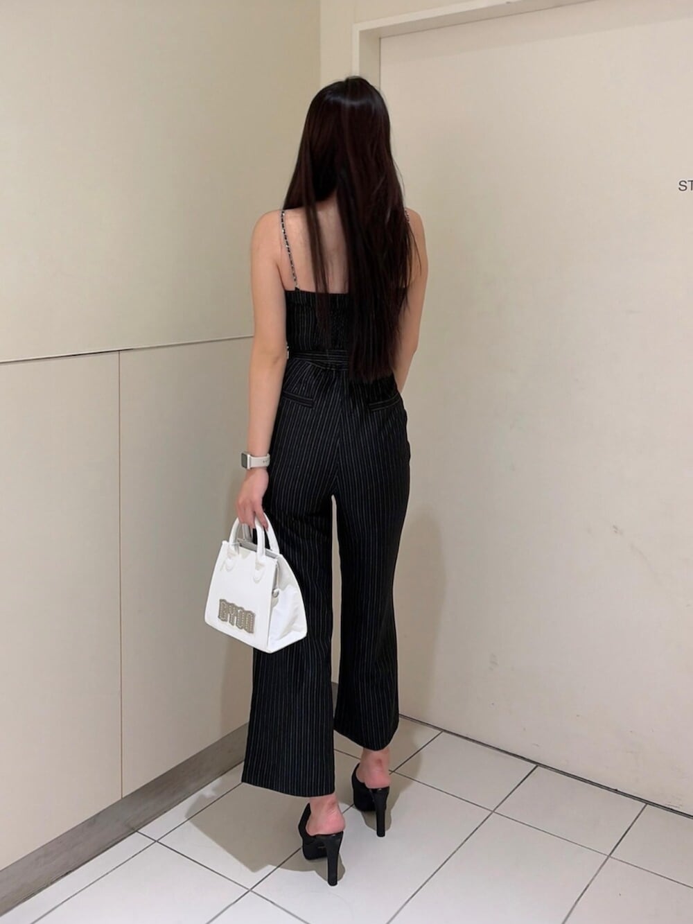 ブラック系のパンプス、ブラック系のつなぎ/オールインワン、ホワイト系のハンドバッグを着用したレディースの秋コーディネートの3枚目の写真