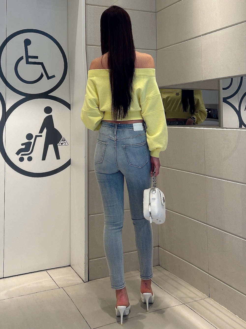 イエロー系のスウェット、ホワイト系のショルダーバッグ、ホワイト系のパンプスを着用したレディースの冬コーディネートの3枚目の写真