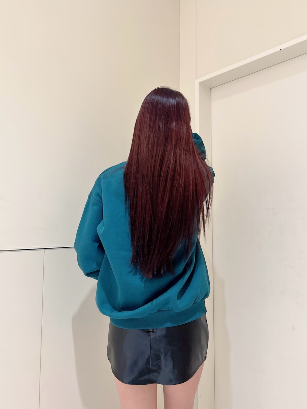 グリーン系のスウェット、ブラック系のスカート、ブラック系のブーツを着用したレディースの冬コーディネートの5枚目の写真