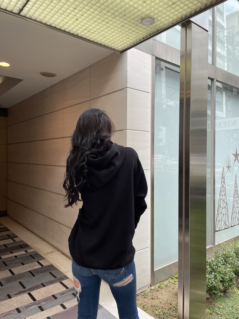 ブルー系のデニムパンツ、ブラック系のスウェット、ブラック系のパンプスを着用したレディースの冬コーディネートの5枚目の写真