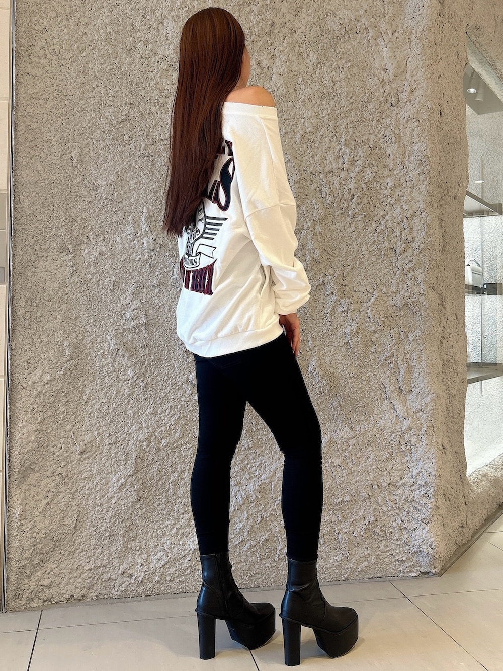 ホワイト系のスウェット、ブラック系のデニムパンツ、ブラック系のブーツを着用したレディースの秋コーディネートの2枚目の写真