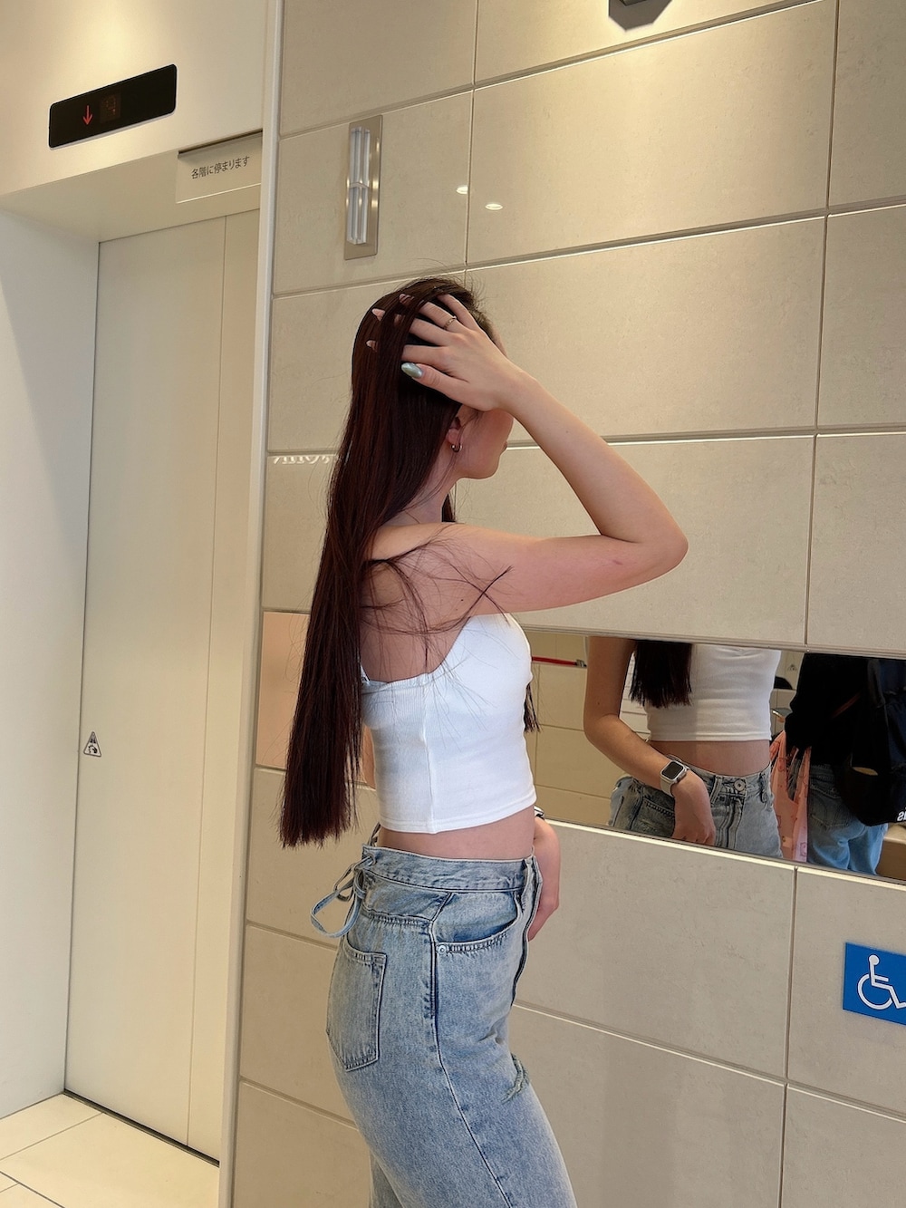 ホワイト系のキャミソール、ブルー系のデニムパンツ、ホワイト系のパンプスを着用したレディースの春コーディネートの5枚目の写真