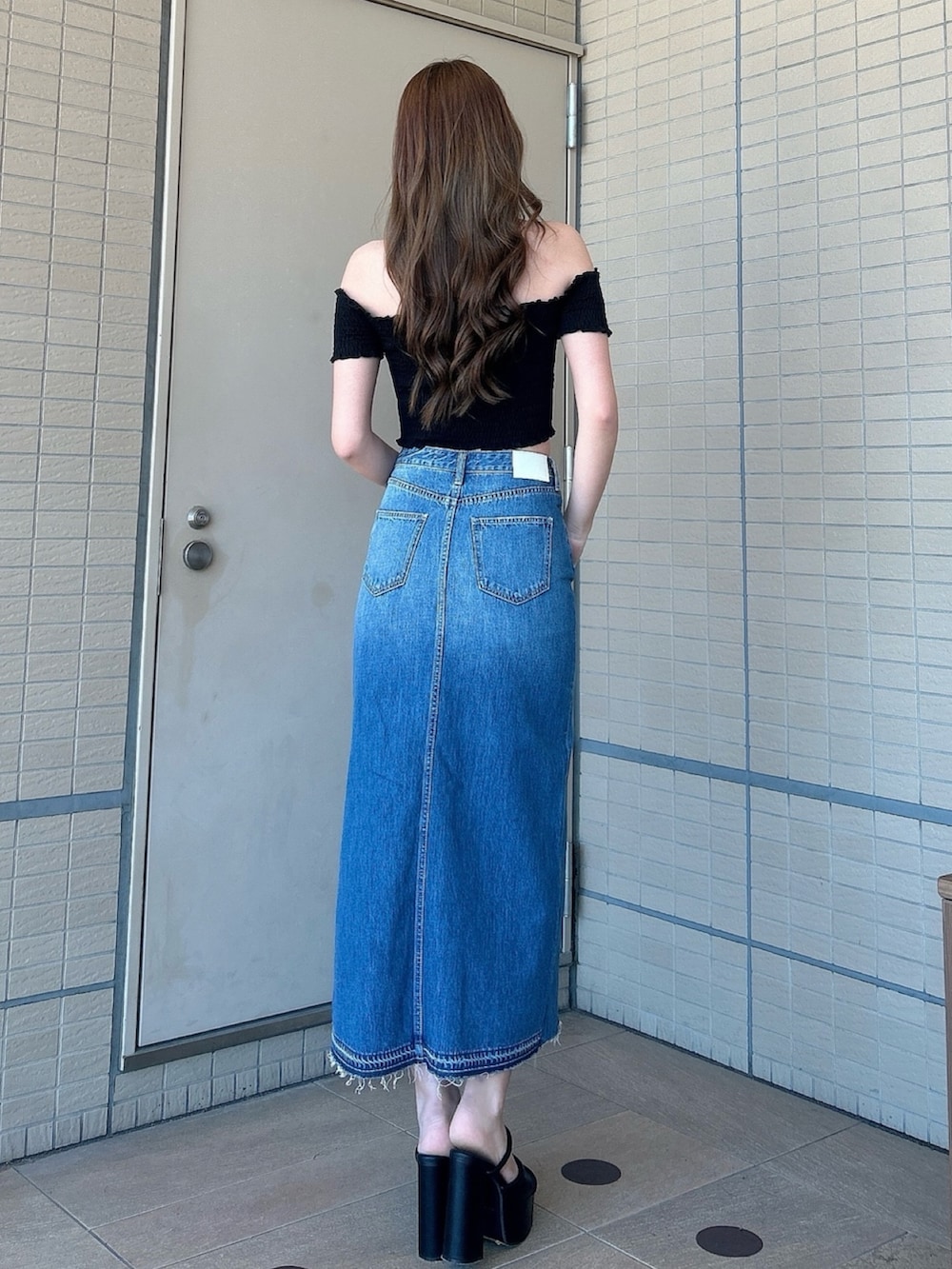 ブラック系のサンダル、ブルー系のデニムスカート、ブラック系のTシャツ/カットソーを着用したレディースの夏コーディネートの3枚目の写真